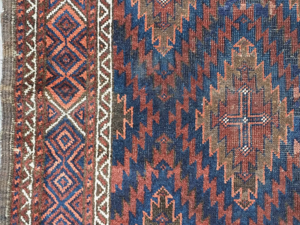 An antique hand-woven Arab Baluch runner rug featuring a dark navy blue and deep red geometric diamond lattice pattern with outer geometric borders. View VII
