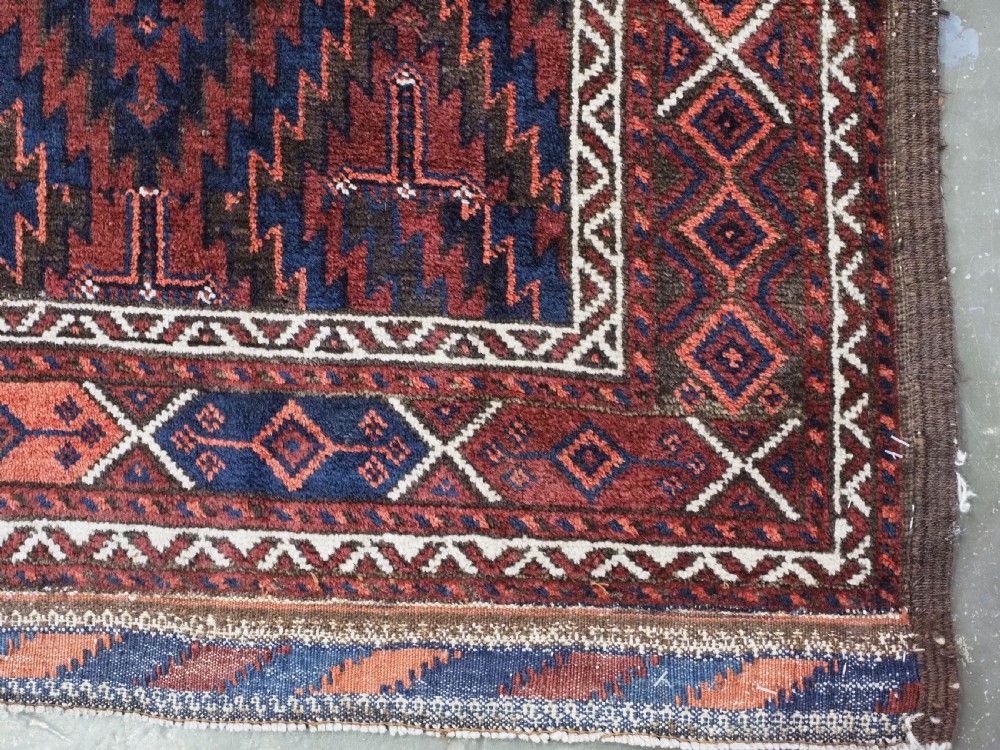 An antique hand-woven Arab Baluch runner rug featuring a dark navy blue and deep red geometric diamond lattice pattern with outer geometric borders. View XII