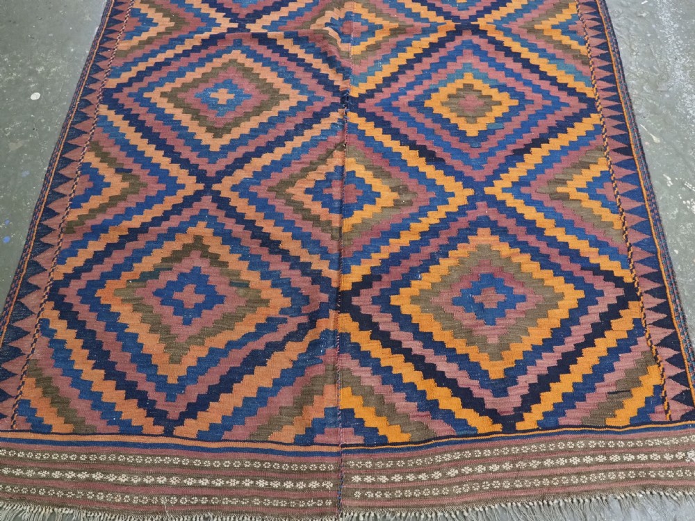An antique flatwoven wool Baluch kilim with repeating geometric diamond patterns in blue, orange, brown, and purple shades, constructed in two joined panels. View IV