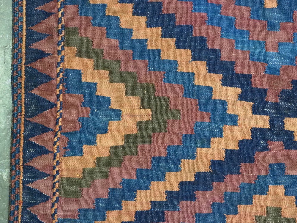 An antique flatwoven wool Baluch kilim with repeating geometric diamond patterns in blue, orange, brown, and purple shades, constructed in two joined panels. View VII