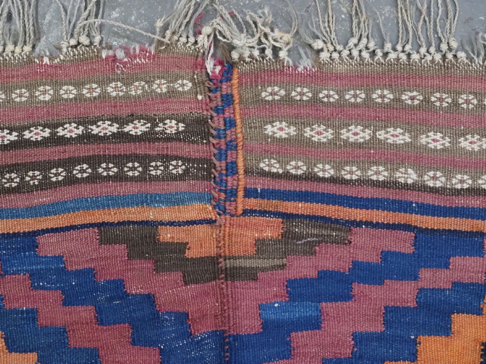 An antique flatwoven wool Baluch kilim with repeating geometric diamond patterns in blue, orange, brown, and purple shades, constructed in two joined panels. View VIII