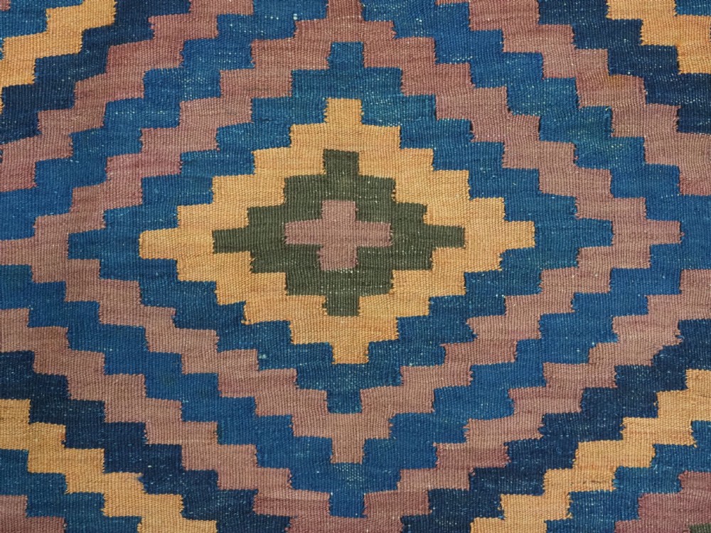An antique flatwoven wool Baluch kilim with repeating geometric diamond patterns in blue, orange, brown, and purple shades, constructed in two joined panels. View IX