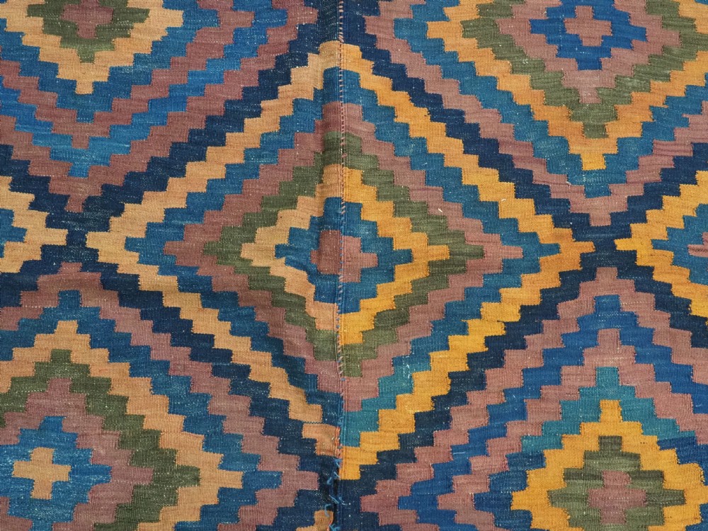 An antique flatwoven wool Baluch kilim with repeating geometric diamond patterns in blue, orange, brown, and purple shades, constructed in two joined panels. View XI