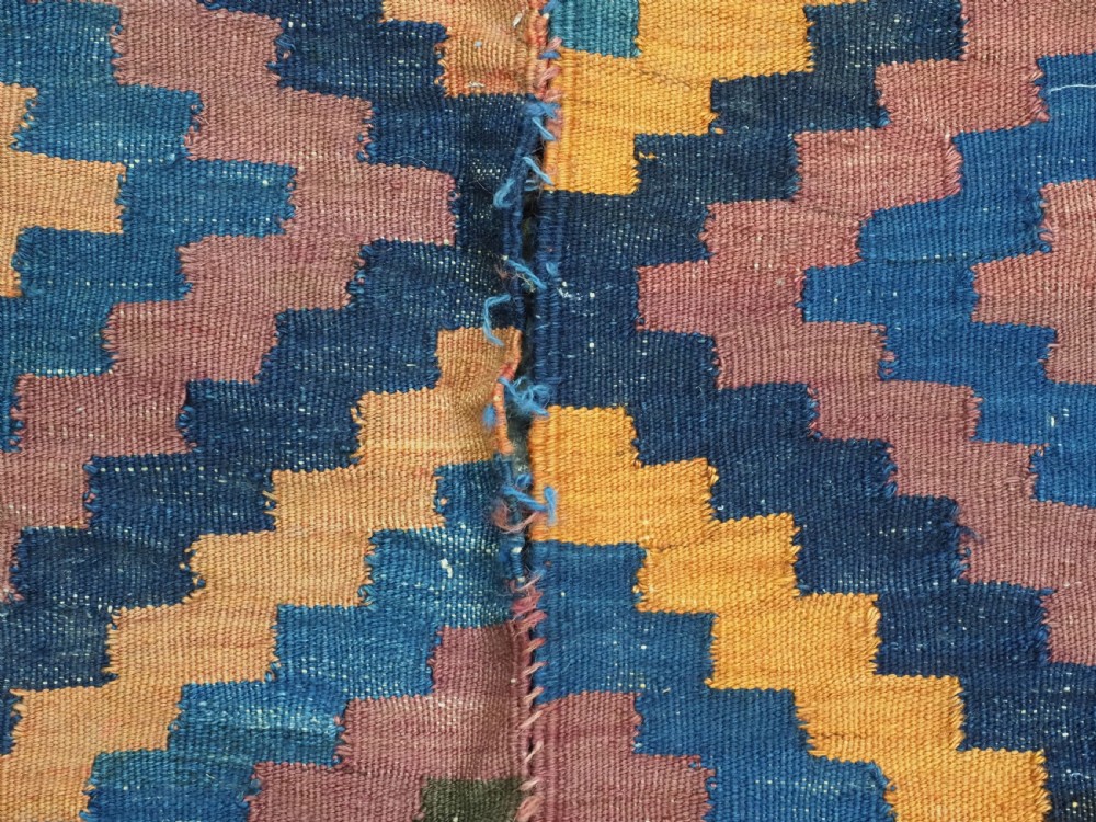 An antique flatwoven wool Baluch kilim with repeating geometric diamond patterns in blue, orange, brown, and purple shades, constructed in two joined panels. View XII