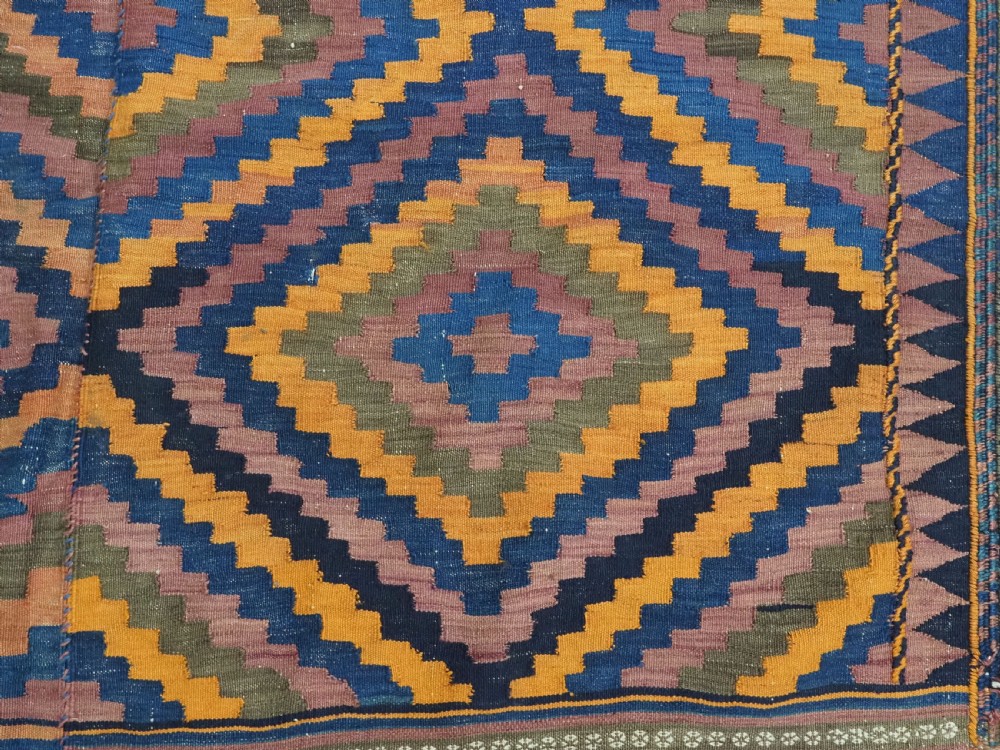 An antique flatwoven wool Baluch kilim with repeating geometric diamond patterns in blue, orange, brown, and purple shades, constructed in two joined panels. View XIII
