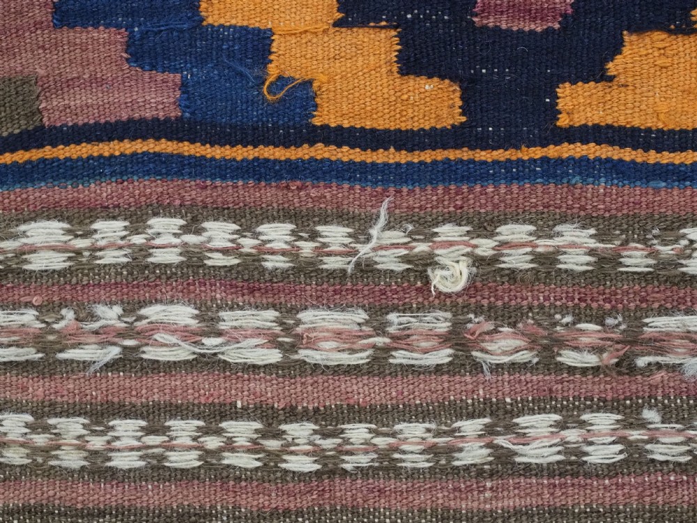An antique flatwoven wool Baluch kilim with repeating geometric diamond patterns in blue, orange, brown, and purple shades, constructed in two joined panels. View XV