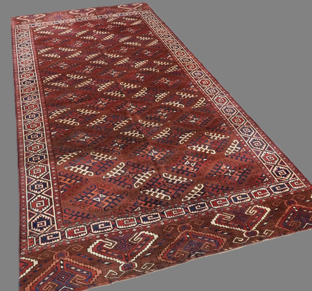A long hand-knotted antique wool rug featuring a repeating dyrnak gul pattern in deep red, navy, and ivory tones surrounded by geometric borders. View II