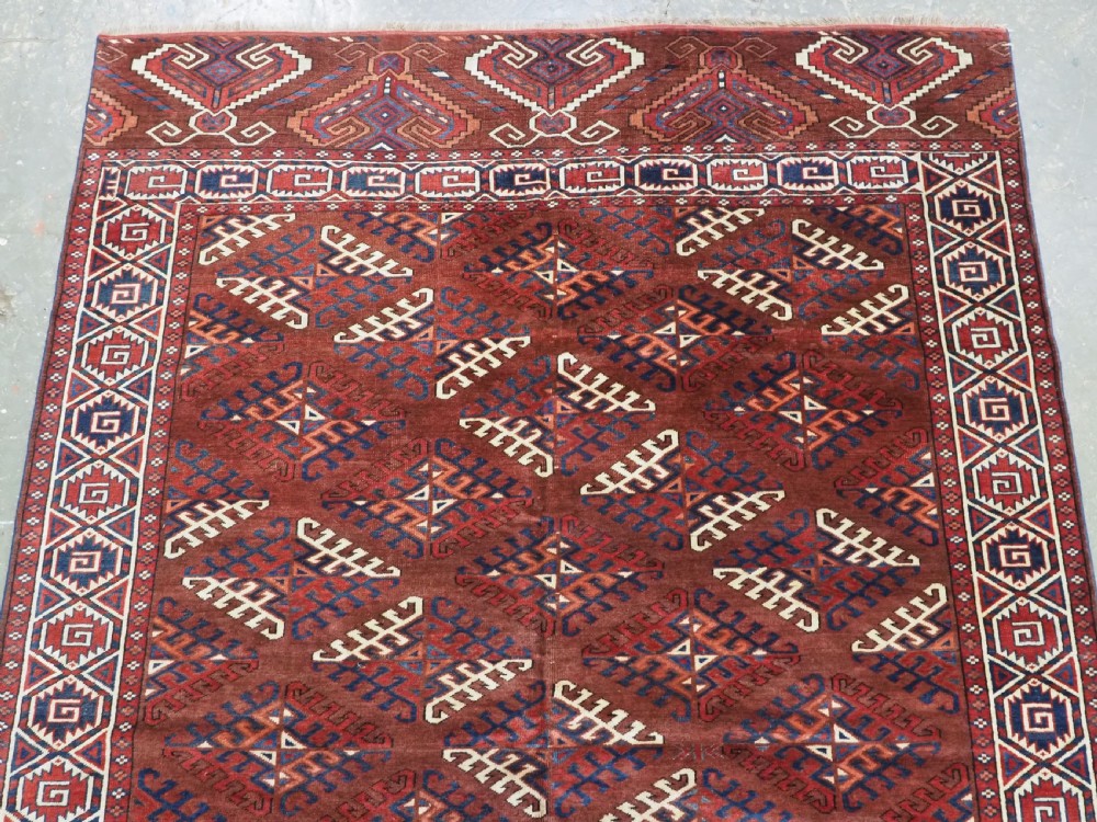 A long hand-knotted antique wool rug featuring a repeating dyrnak gul pattern in deep red, navy, and ivory tones surrounded by geometric borders. View III