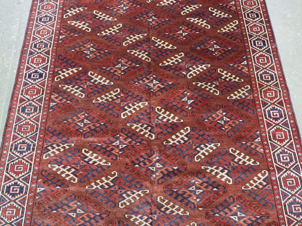 A long hand-knotted antique wool rug featuring a repeating dyrnak gul pattern in deep red, navy, and ivory tones surrounded by geometric borders. View IV