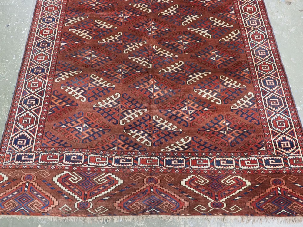 A long hand-knotted antique wool rug featuring a repeating dyrnak gul pattern in deep red, navy, and ivory tones surrounded by geometric borders. View V