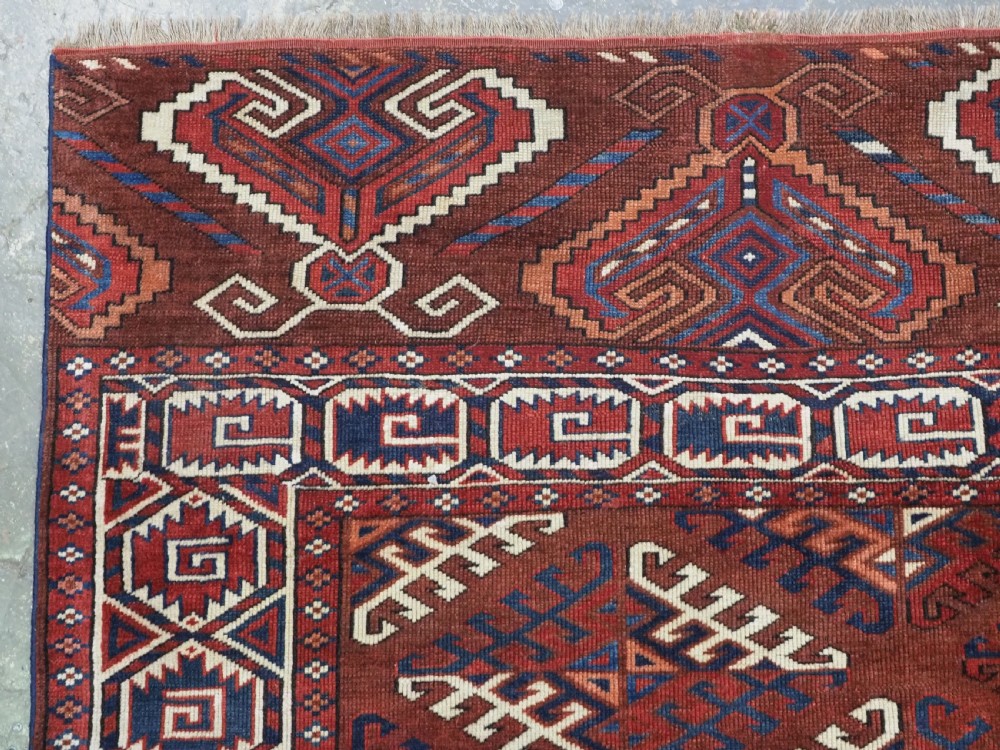 A long hand-knotted antique wool rug featuring a repeating dyrnak gul pattern in deep red, navy, and ivory tones surrounded by geometric borders. View VI