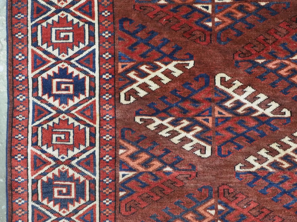 A long hand-knotted antique wool rug featuring a repeating dyrnak gul pattern in deep red, navy, and ivory tones surrounded by geometric borders. View VII