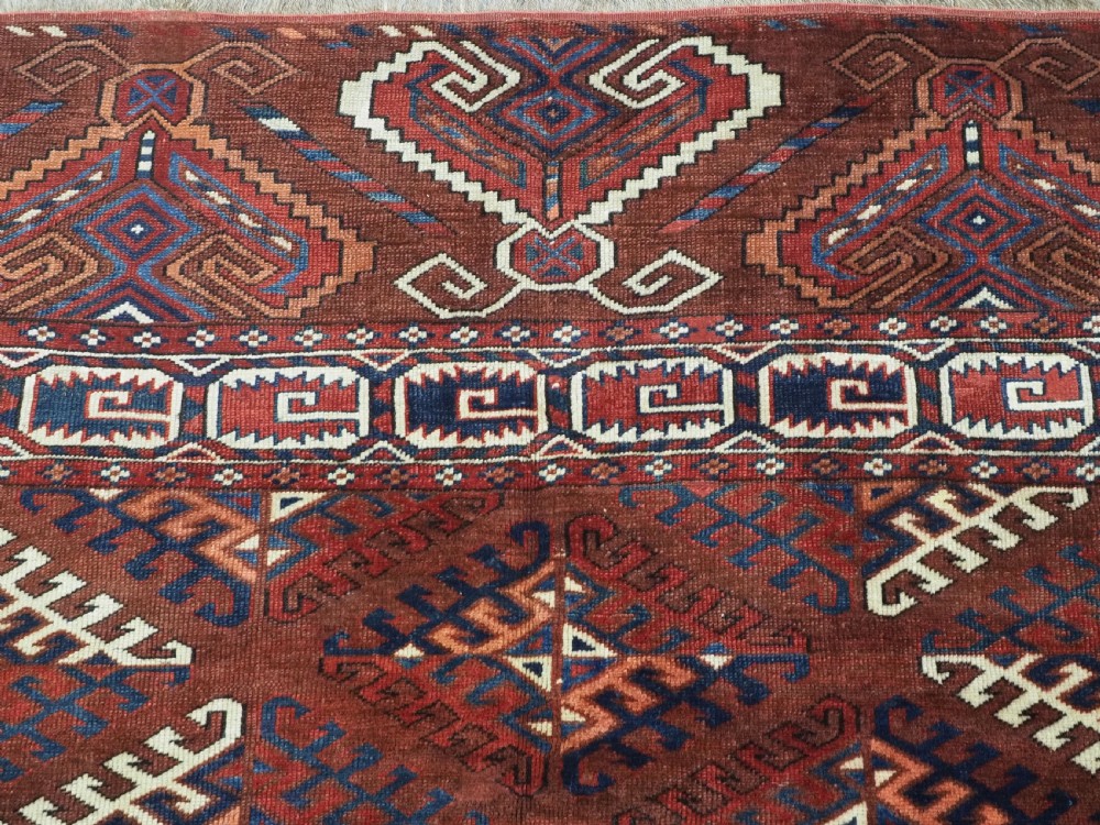 A long hand-knotted antique wool rug featuring a repeating dyrnak gul pattern in deep red, navy, and ivory tones surrounded by geometric borders. View VIII