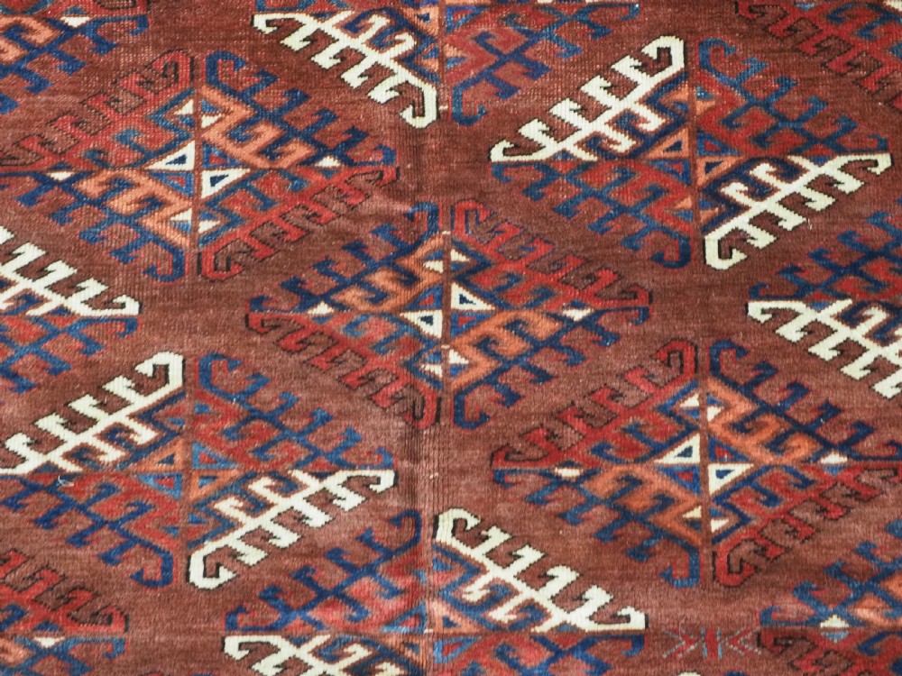 A long hand-knotted antique wool rug featuring a repeating dyrnak gul pattern in deep red, navy, and ivory tones surrounded by geometric borders. View IX