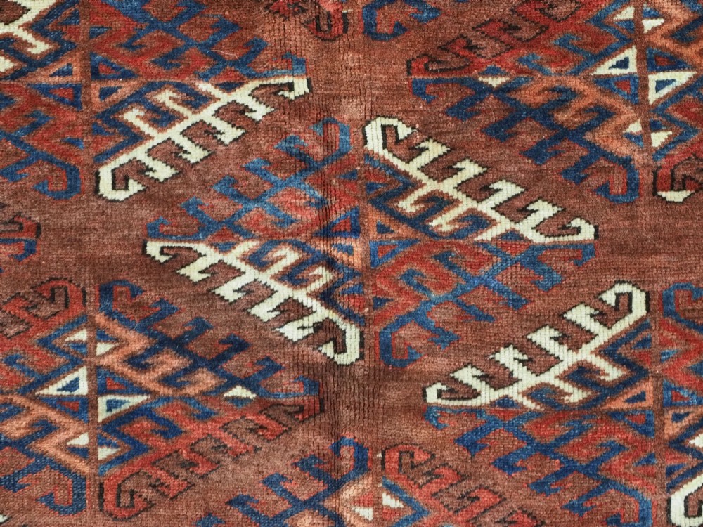 A long hand-knotted antique wool rug featuring a repeating dyrnak gul pattern in deep red, navy, and ivory tones surrounded by geometric borders. View XI