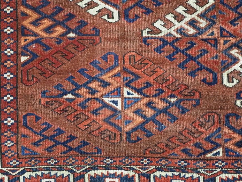 A long hand-knotted antique wool rug featuring a repeating dyrnak gul pattern in deep red, navy, and ivory tones surrounded by geometric borders. View XII