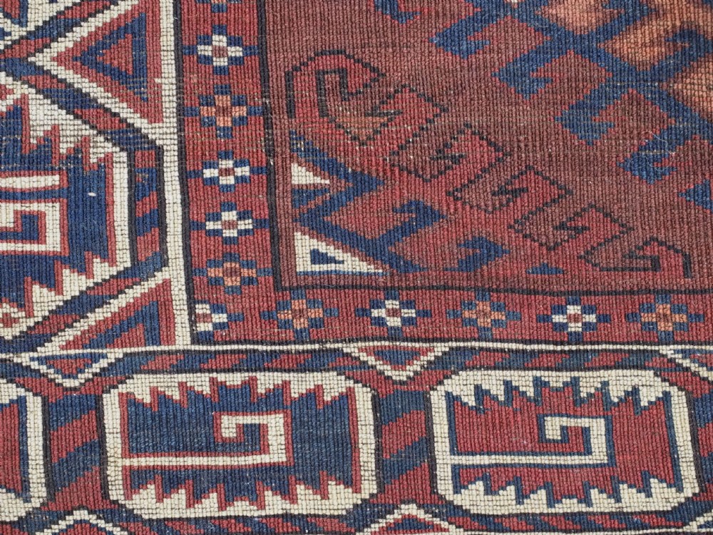 A long hand-knotted antique wool rug featuring a repeating dyrnak gul pattern in deep red, navy, and ivory tones surrounded by geometric borders. View XV