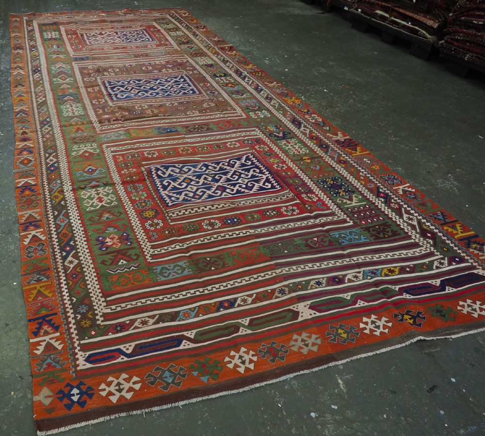 An antique Turkish Reyhanli flatweave kilim runner featuring multi-coloured geometric medallions joined along a central seam with a red border. View II