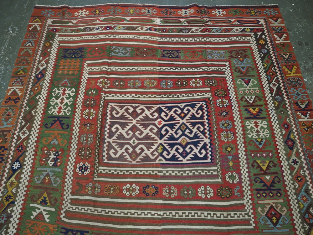 An antique Turkish Reyhanli flatweave kilim runner featuring multi-coloured geometric medallions joined along a central seam with a red border. View III