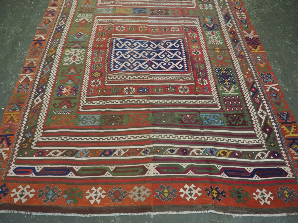 An antique Turkish Reyhanli flatweave kilim runner featuring multi-coloured geometric medallions joined along a central seam with a red border. View V
