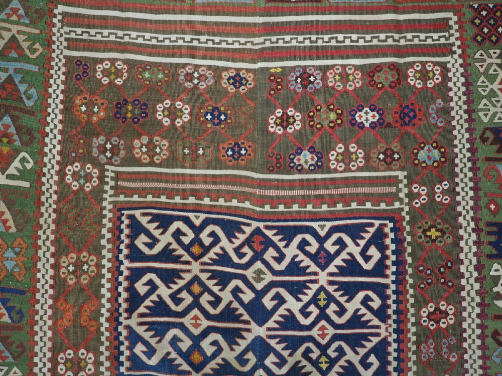 An antique Turkish Reyhanli flatweave kilim runner featuring multi-coloured geometric medallions joined along a central seam with a red border. View X