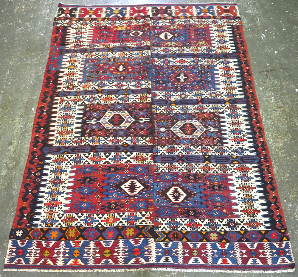 An antique Turkish Bergama Karakecili flatweave kilim rug featuring bold geometric diamond motifs woven in two connected vertical sections in shades of red, navy blue, and cream.