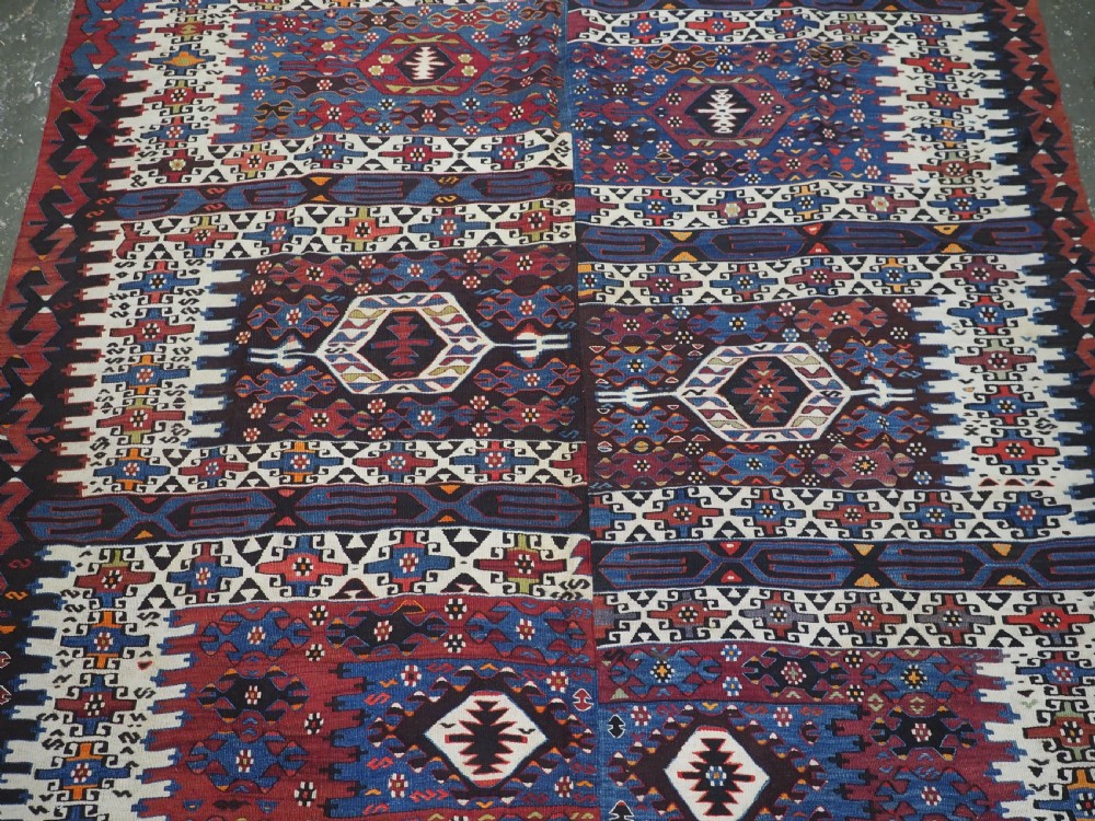 An antique Turkish Bergama Karakecili flatweave kilim rug featuring bold geometric diamond motifs woven in two connected vertical sections in shades of red, navy blue, and cream. View IV