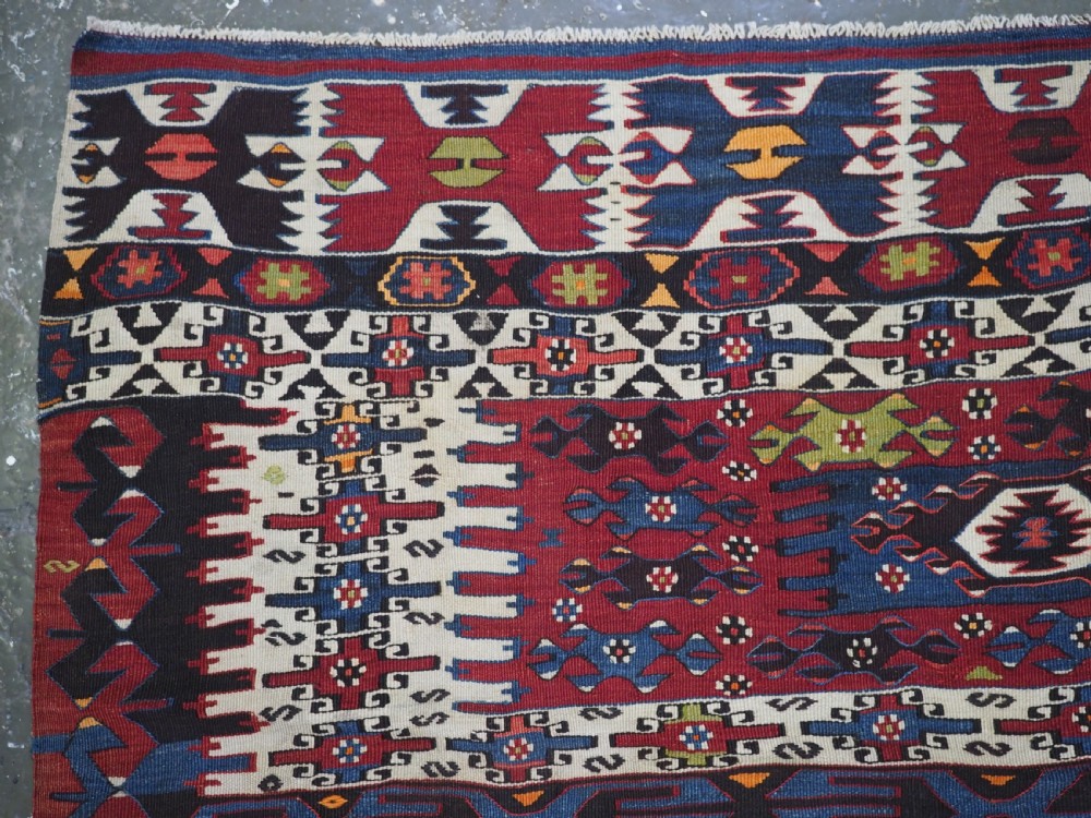 An antique Turkish Bergama Karakecili flatweave kilim rug featuring bold geometric diamond motifs woven in two connected vertical sections in shades of red, navy blue, and cream. View V