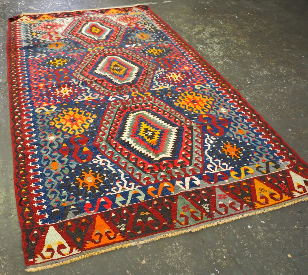 A handwoven Turkish Esme kilim rug displaying geometric diamond medallions in red, blue, yellow, and green wool. View II