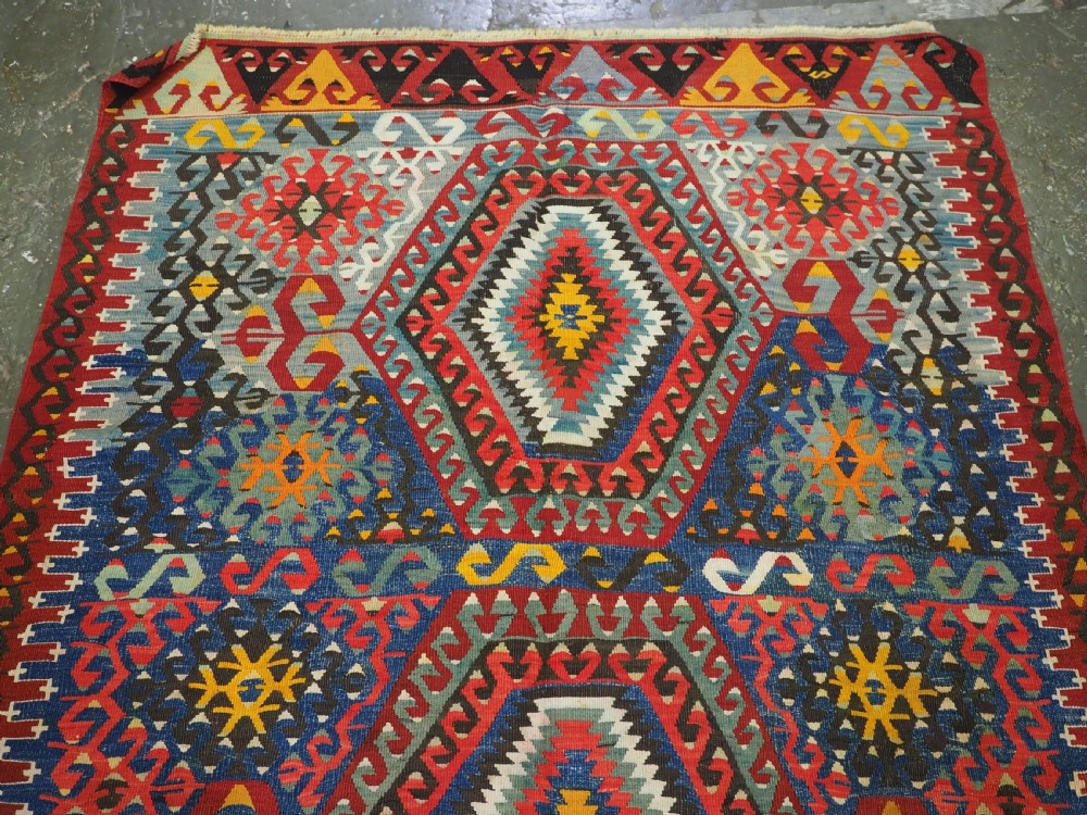 A handwoven Turkish Esme kilim rug displaying geometric diamond medallions in red, blue, yellow, and green wool. View III