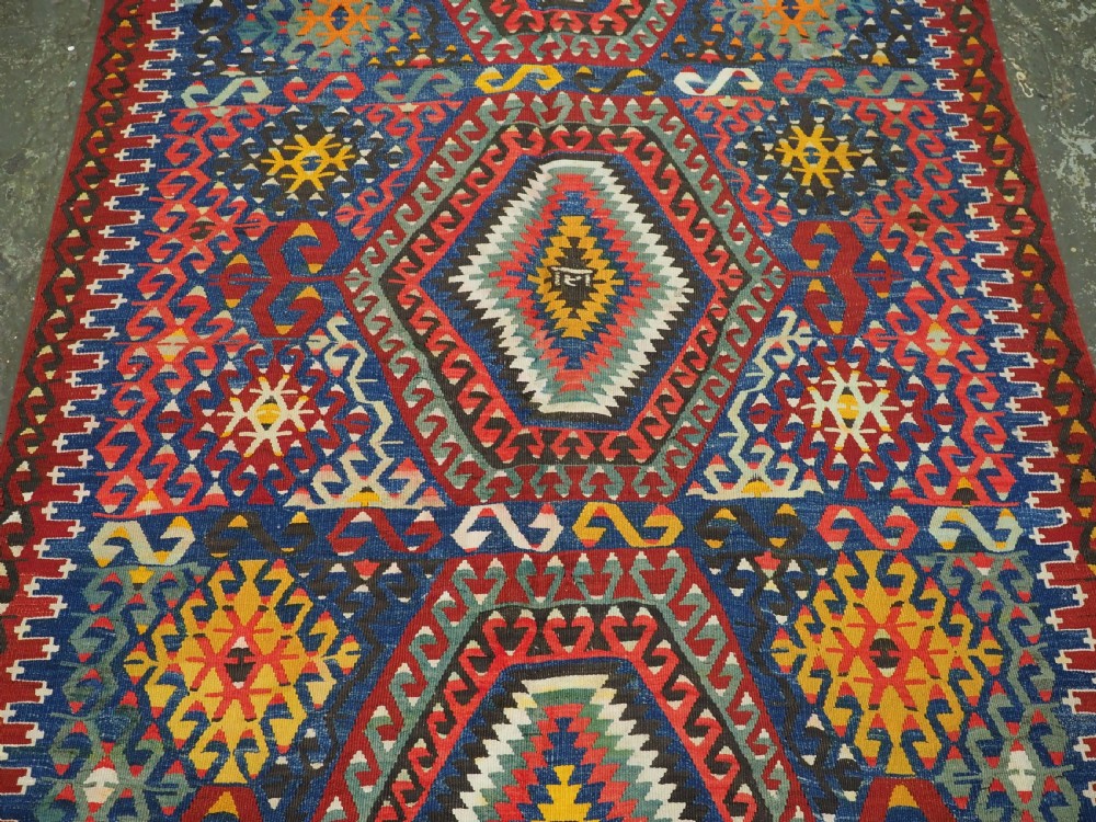 A handwoven Turkish Esme kilim rug displaying geometric diamond medallions in red, blue, yellow, and green wool. View IV