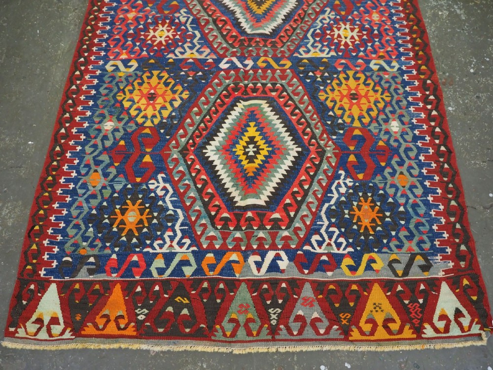 A handwoven Turkish Esme kilim rug displaying geometric diamond medallions in red, blue, yellow, and green wool. View VI