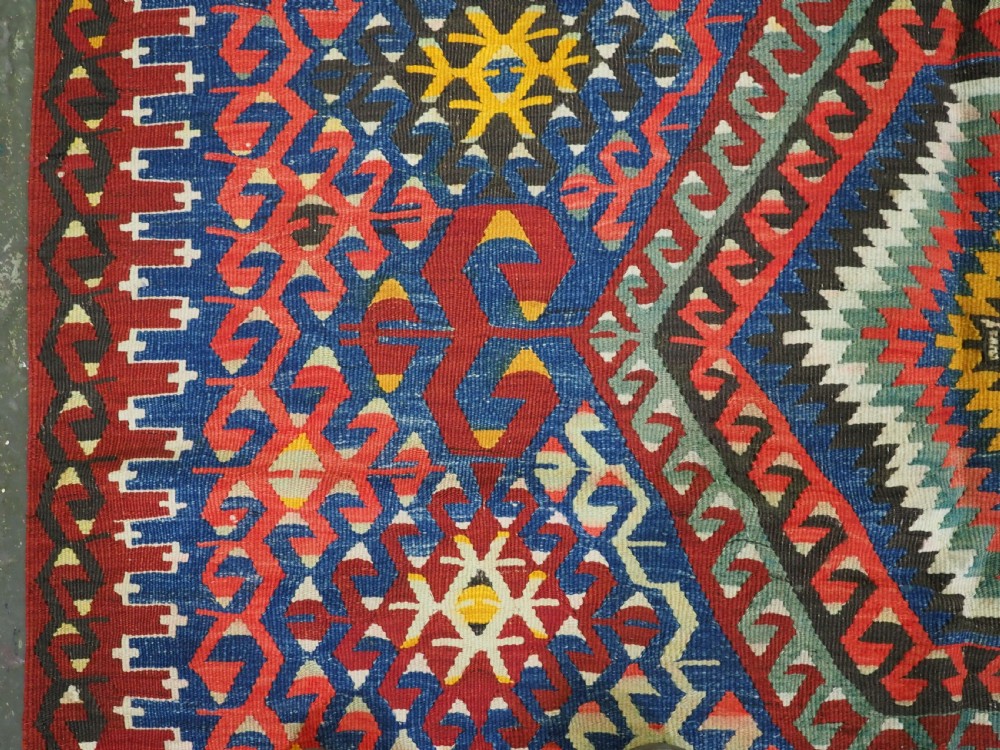 A handwoven Turkish Esme kilim rug displaying geometric diamond medallions in red, blue, yellow, and green wool. View VII