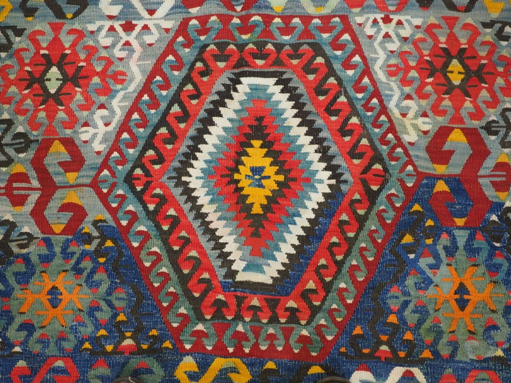 A handwoven Turkish Esme kilim rug displaying geometric diamond medallions in red, blue, yellow, and green wool. View VIII