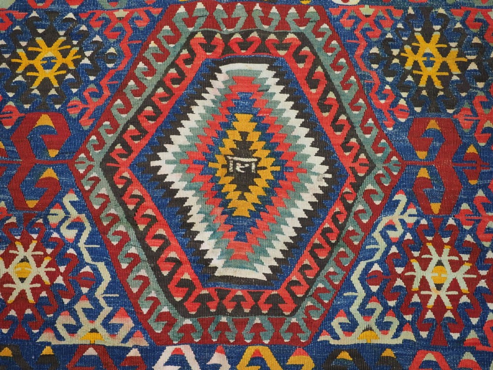 A handwoven Turkish Esme kilim rug displaying geometric diamond medallions in red, blue, yellow, and green wool. View IX