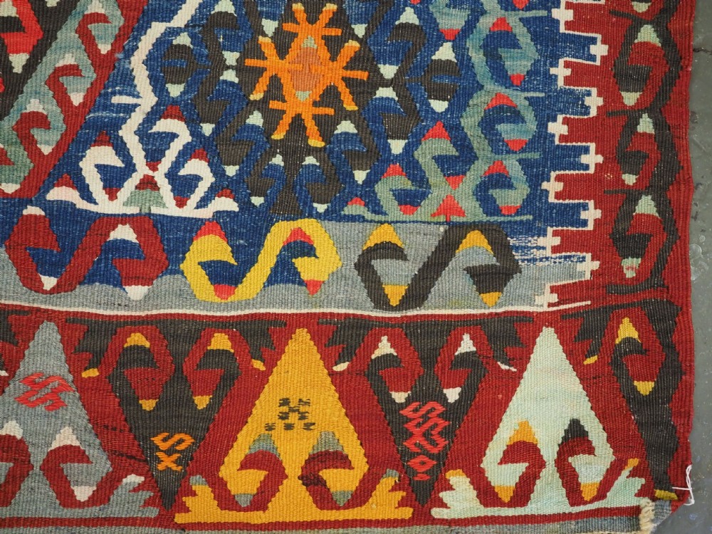 A handwoven Turkish Esme kilim rug displaying geometric diamond medallions in red, blue, yellow, and green wool. View XII