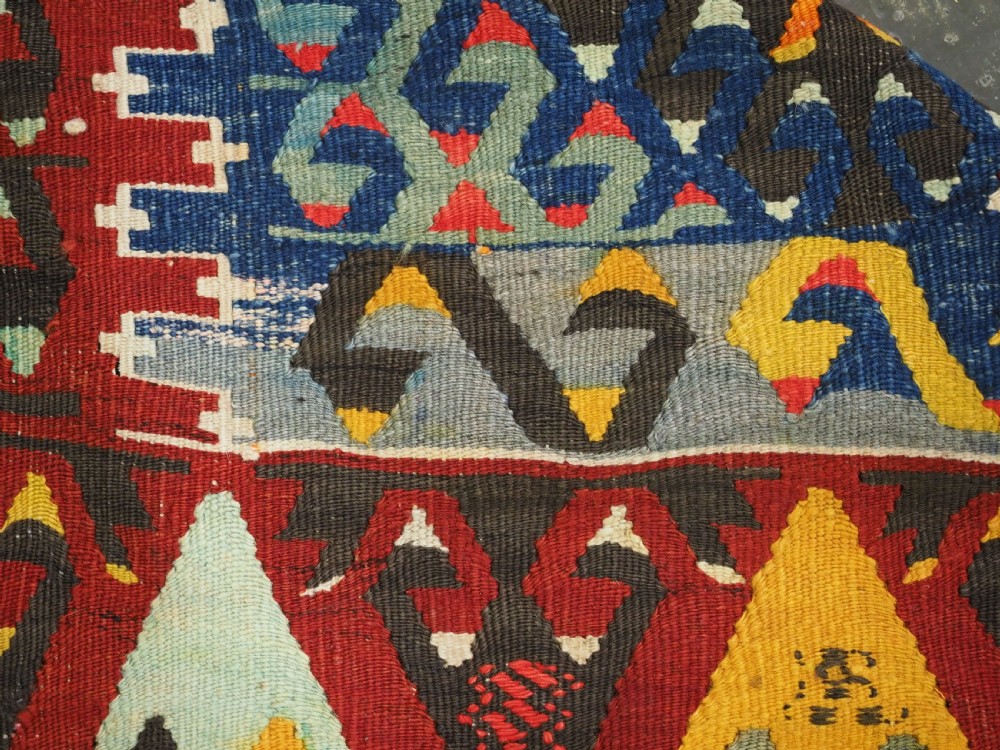 A handwoven Turkish Esme kilim rug displaying geometric diamond medallions in red, blue, yellow, and green wool. View XIII