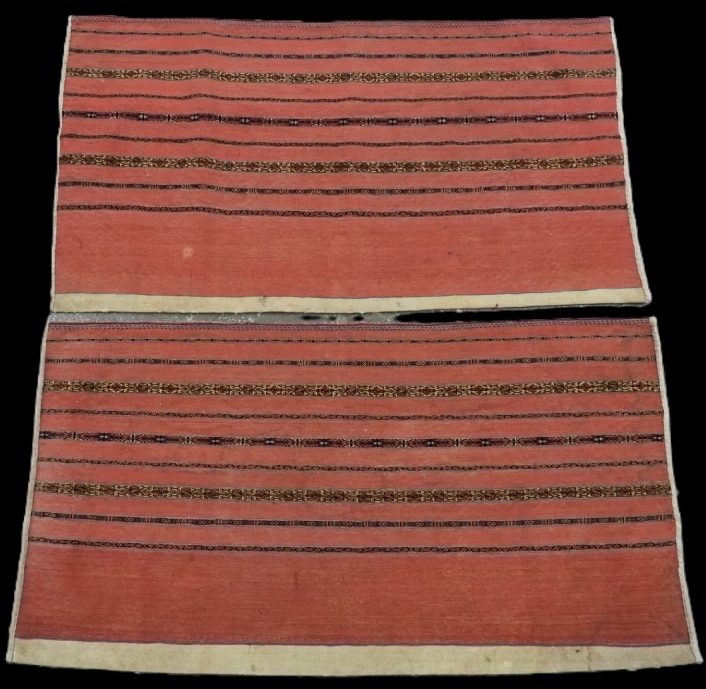 A pair of rectangular antique Turkmen Kizil chuval woven textiles in terracotta red with thin horizontal geometric bands and cream backing edges.
