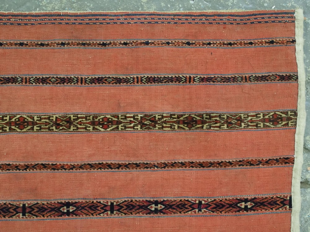 A pair of rectangular antique Turkmen Kizil chuval woven textiles in terracotta red with thin horizontal geometric bands and cream backing edges. View X
