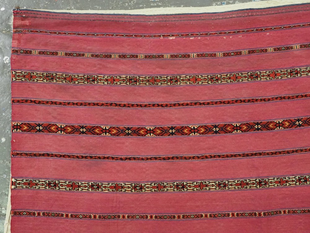 An antique rectangular Tekke Turkmen Kizil chuval woven textile with detailed horizontal geometric bands across a magenta red wool field. View II