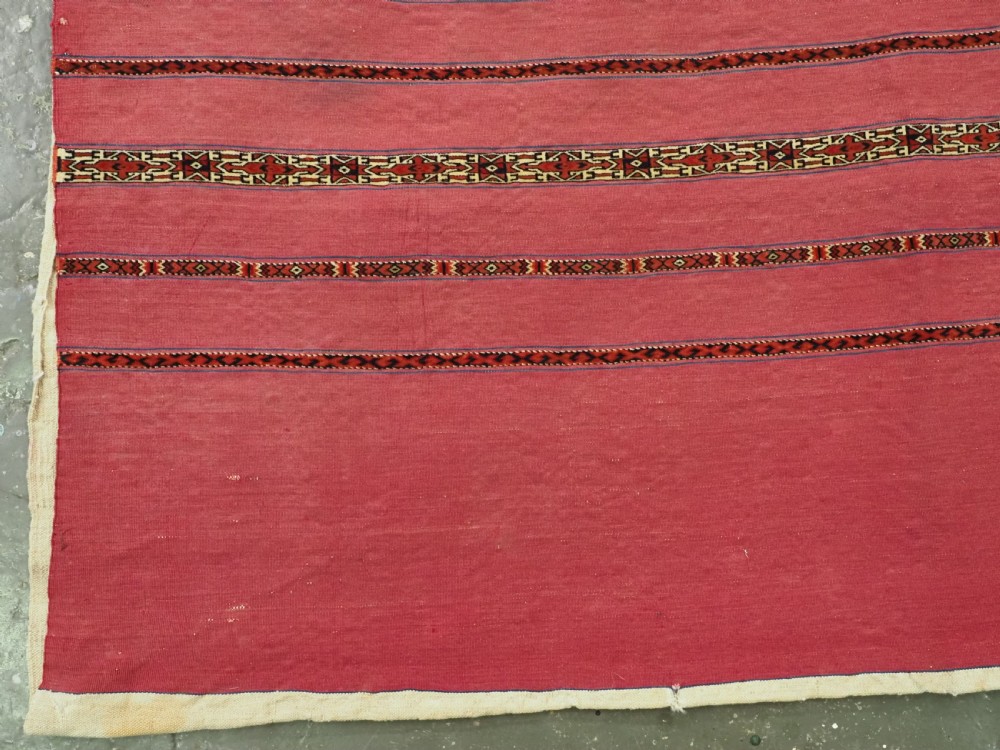 An antique rectangular Tekke Turkmen Kizil chuval woven textile with detailed horizontal geometric bands across a magenta red wool field. View III
