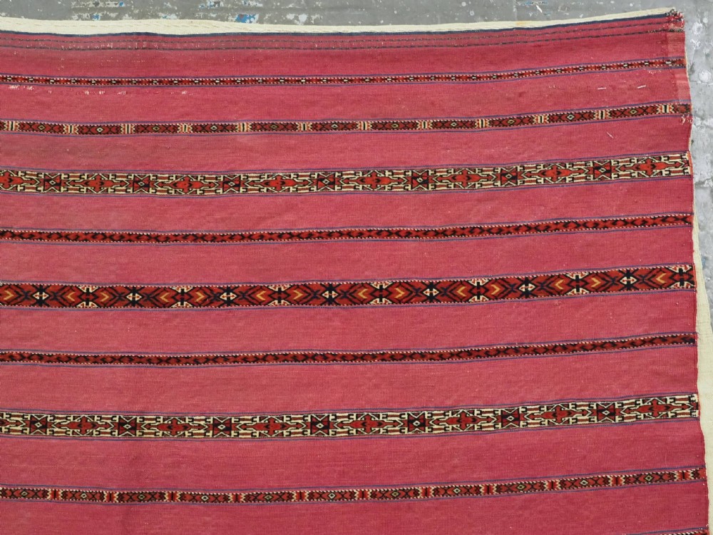 An antique rectangular Tekke Turkmen Kizil chuval woven textile with detailed horizontal geometric bands across a magenta red wool field. View IV