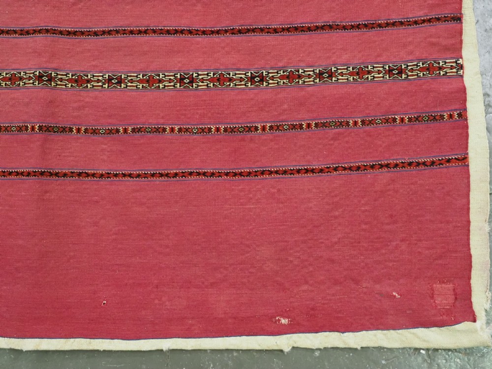 An antique rectangular Tekke Turkmen Kizil chuval woven textile with detailed horizontal geometric bands across a magenta red wool field. View V