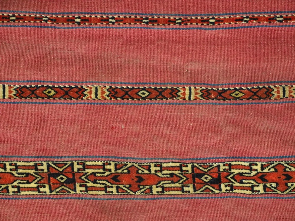 An antique rectangular Tekke Turkmen Kizil chuval woven textile with detailed horizontal geometric bands across a magenta red wool field. View VI
