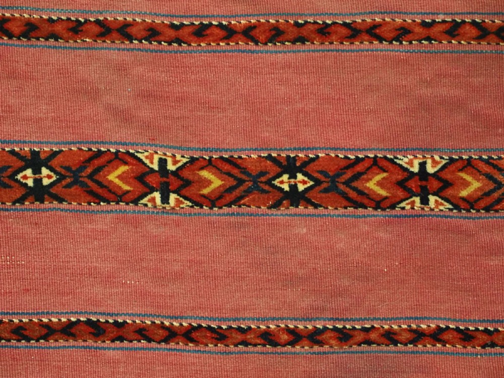 An antique rectangular Tekke Turkmen Kizil chuval woven textile with detailed horizontal geometric bands across a magenta red wool field. View VII