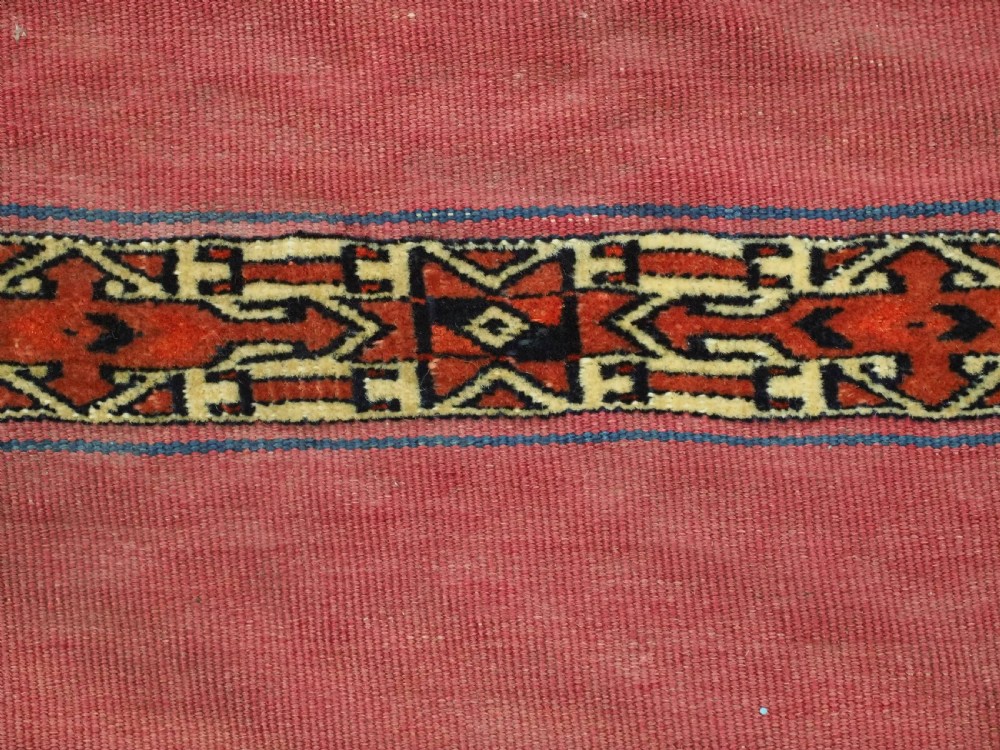 An antique rectangular Tekke Turkmen Kizil chuval woven textile with detailed horizontal geometric bands across a magenta red wool field. View IX