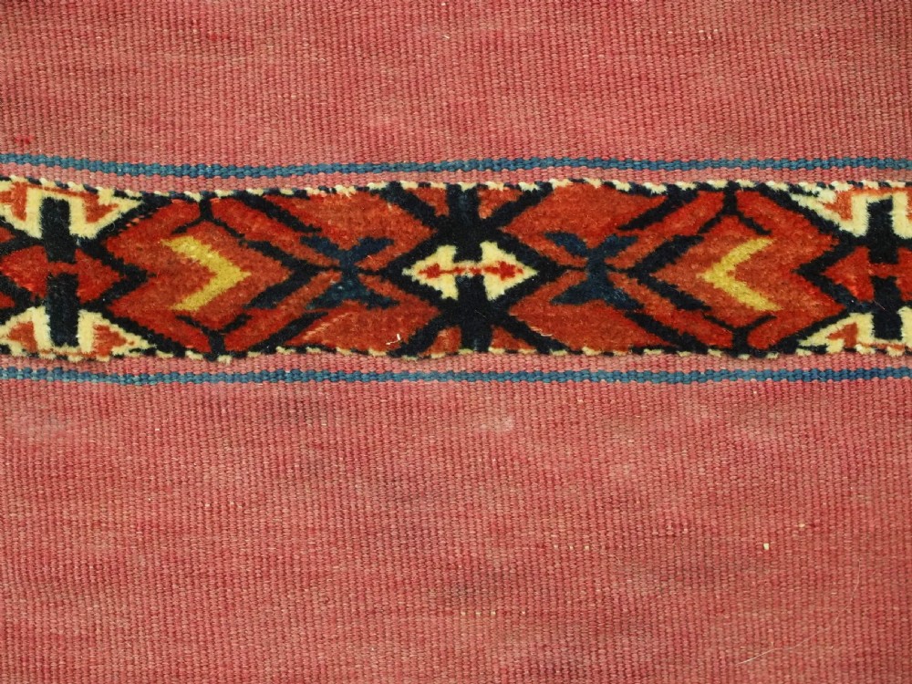 An antique rectangular Tekke Turkmen Kizil chuval woven textile with detailed horizontal geometric bands across a magenta red wool field. View X
