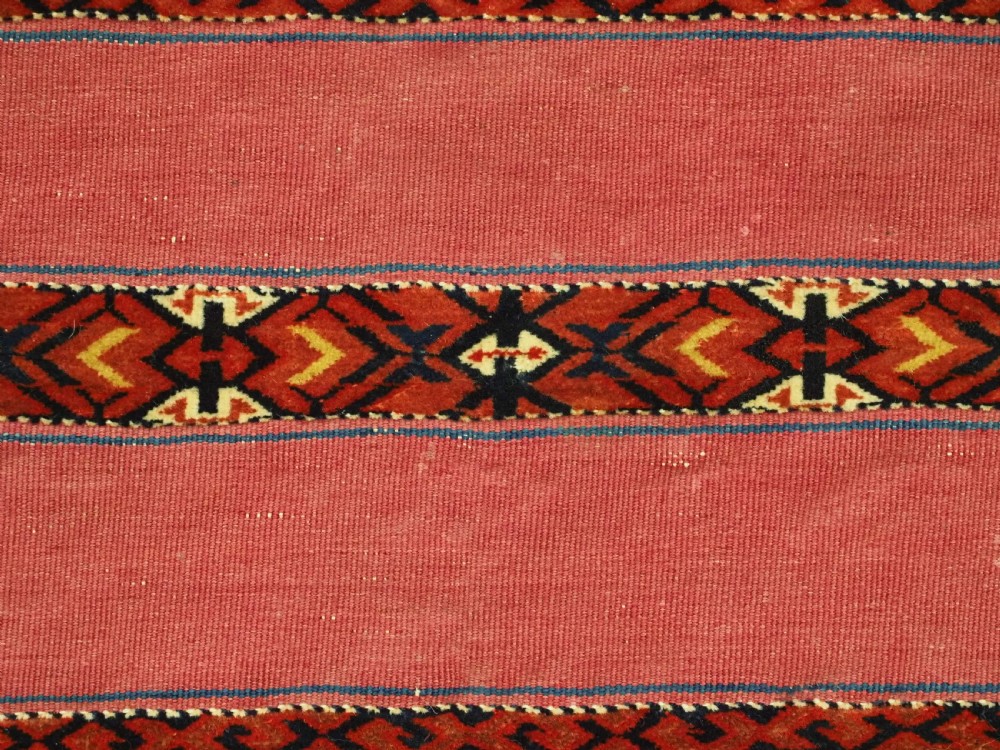 An antique rectangular Tekke Turkmen Kizil chuval woven textile with detailed horizontal geometric bands across a magenta red wool field. View XII