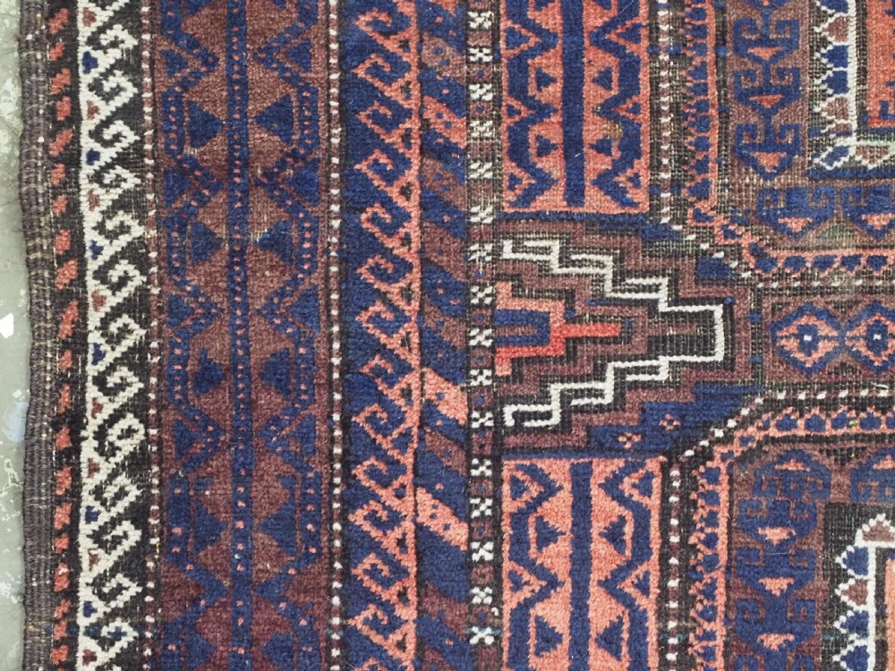 An antique rectangular Baluch tribal rug featuring five central geometric box medallions in dark red and indigo blue against a patterned ground. View VII
