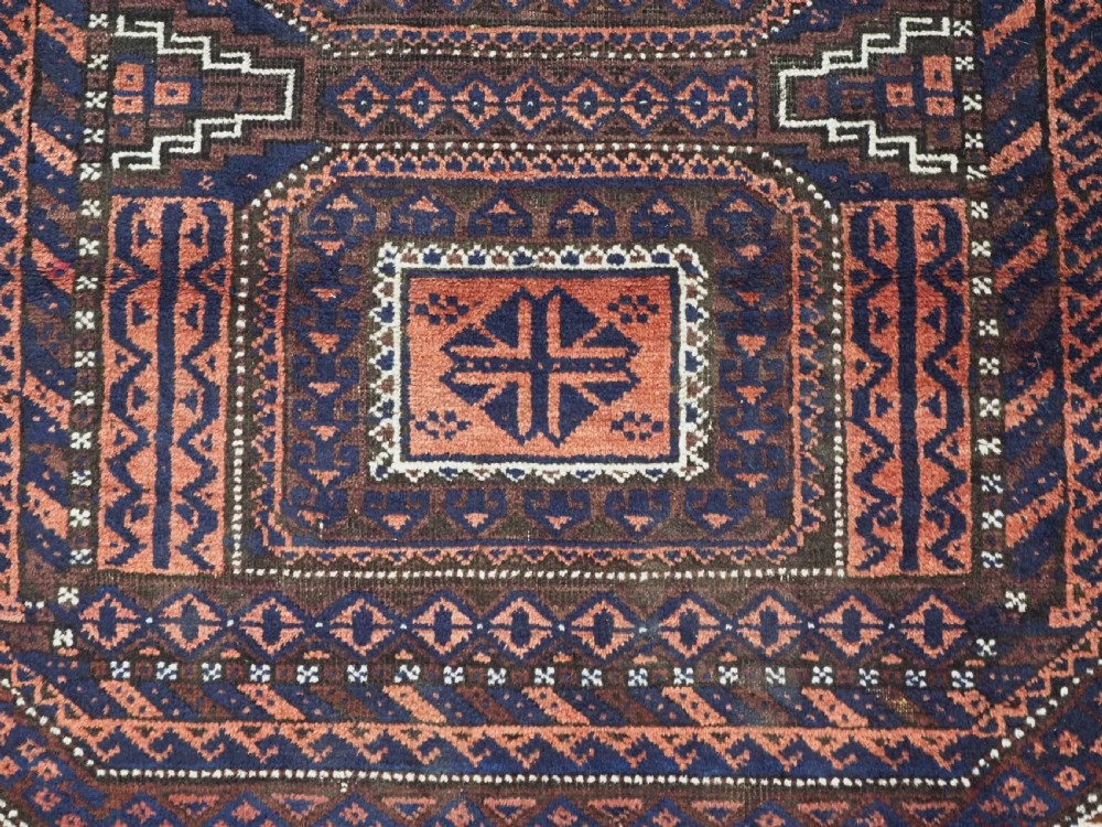 An antique rectangular Baluch tribal rug featuring five central geometric box medallions in dark red and indigo blue against a patterned ground. View IX